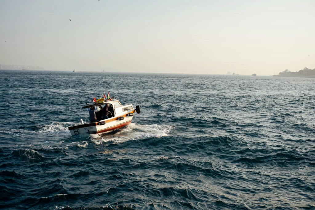A small fishing boat sails on a calm sea under a clear sky, capturing a peaceful maritime scene.